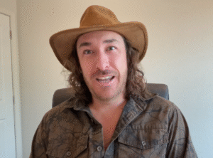 Jeff Zausch wearing a brown hat and patterned shirt while speaking in an online interview about survival and resilience
