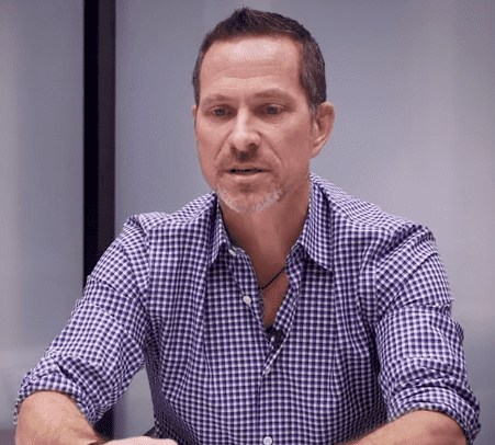 "Professional portrait of Alec Litowitz, wearing a checkered blue shirt, speaking in a modern office setting, highlighting his role as a hedge fund manager and founder of Magnetar Capital." Alec Litowitz Net Worth